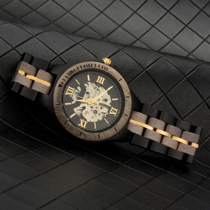Elegant wooden watch with leather strap on leather surface.