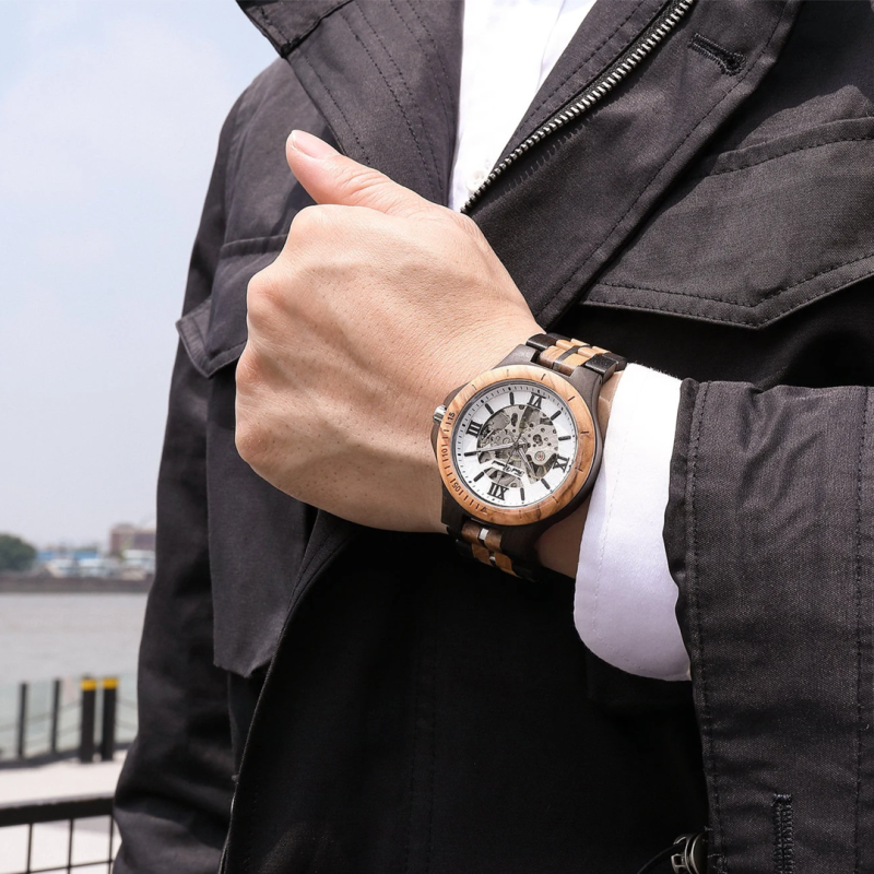 Wooden wristwatch on person's hand with jacket.