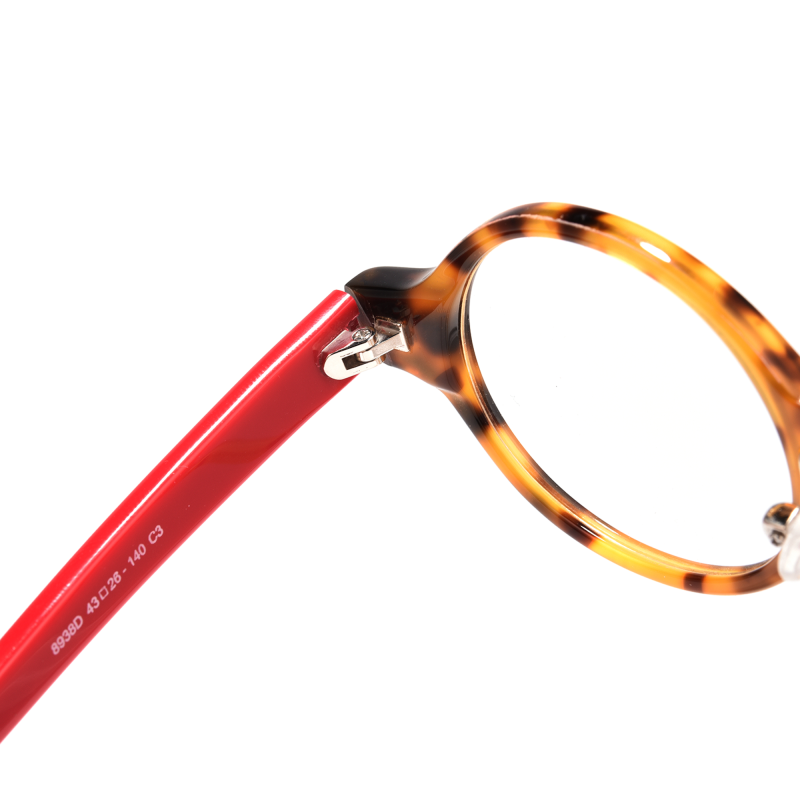 Tortoiseshell glasses with red temples, close-up view.